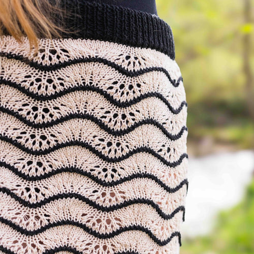 Nahaufnahme einer Frau in einem Lochstrick-Muster Rock mit Wellenmuster in Schwarz und Beige, ideal für den Sommer. Der Rock wurde aus einem Baumwollgarn - Lang Yarns Oceania gestrickt.